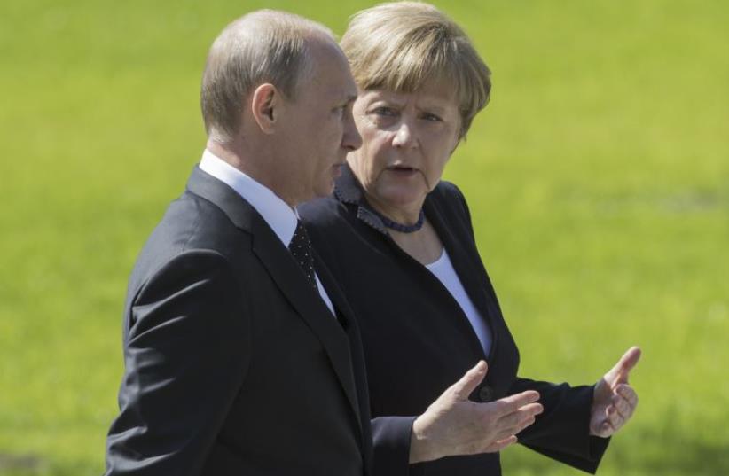 Russian President Vladimir Putin (L) listens to German Chancellor Angela Merkel as they attend a wreath-laying ceremony at the Tomb of the Unknown Soldier in Moscow (photo credit: REUTERS)