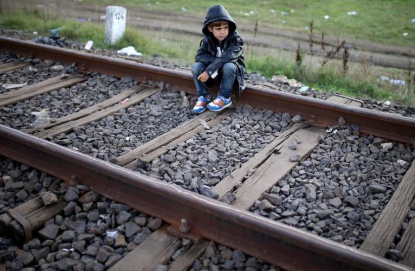 A migrant boy rests on railways after crossing into the country from Serbia at the border near Roszke, Hungary (photo credit: REUTERS)
