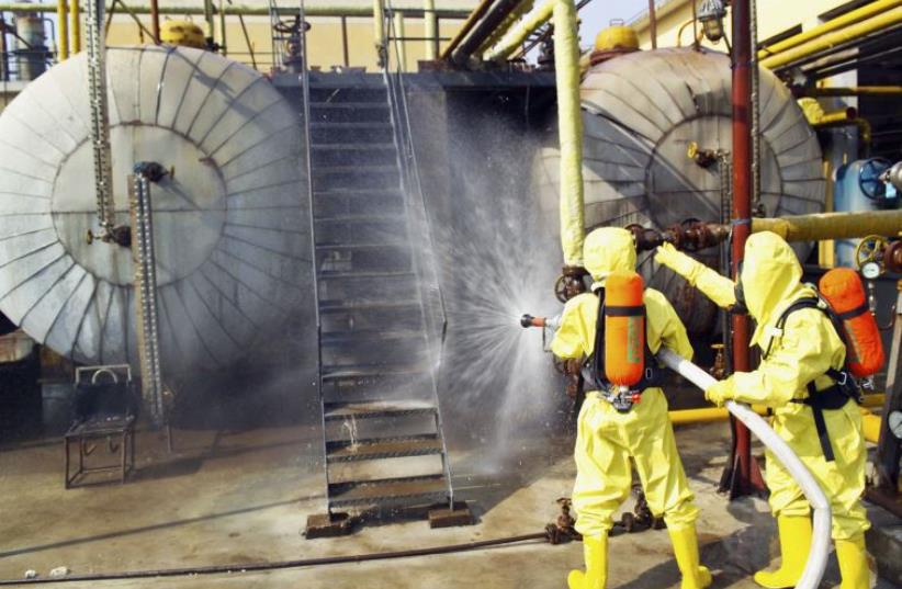 Firefighters use water to dilute ammonia leaking from a chemical plant (photo credit: REUTERS)