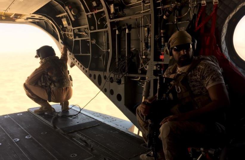 A soldier and an airman from the United Arab Emirates sit in a helicopter flying a small group of journalists to the Marib in central Yemen, September 14, 2015. (photo credit: REUTERS)