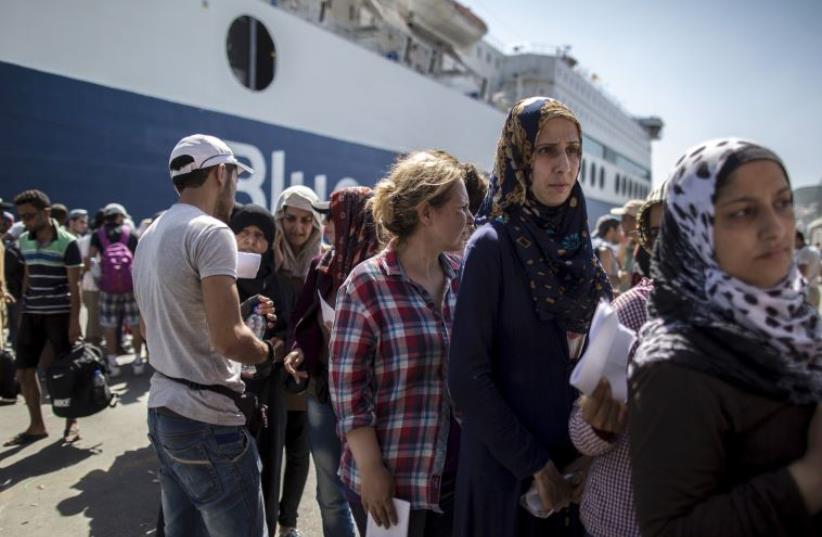 Syrian migrants queue with others to buy a ticket for a ferry trip to Athens from the Greek island of Lesbos  (photo credit: REUTERS)