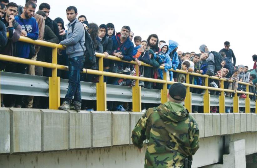 A thousand migrants crowd a bridge crossing from Greece into Macedonia. They are leaving refugee camps in the hope of a new life (photo credit: SETH J. FRANTZMAN)