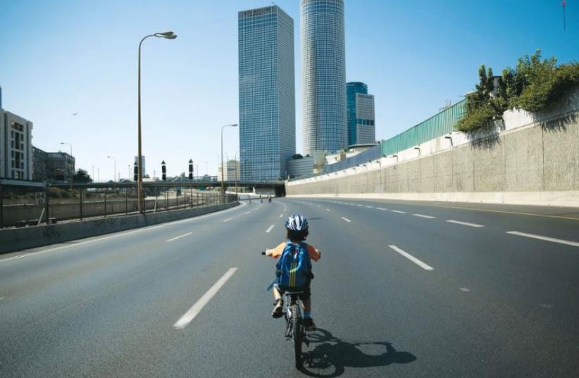 A boy rides his bike on the empty Ayalon highway on Yom Kippur (photo credit: REUTERS)
