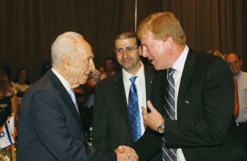 Former president Shimon Peres meets with Myron Brilliant, with US Ambassador to Israel Dan Shapiro in the background (photo credit: SIVAN FARAG)