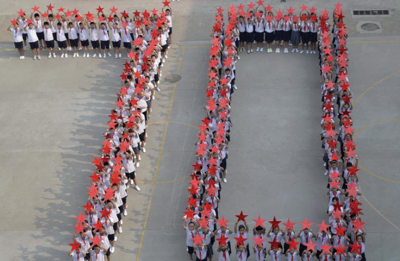 STUDENTS FORM the figure ‘70’ earlier this month as they pose with Chinese national flags and red stars during an event to mark the 70th anniversary of the victory over Japan. (photo credit: REUTERS)