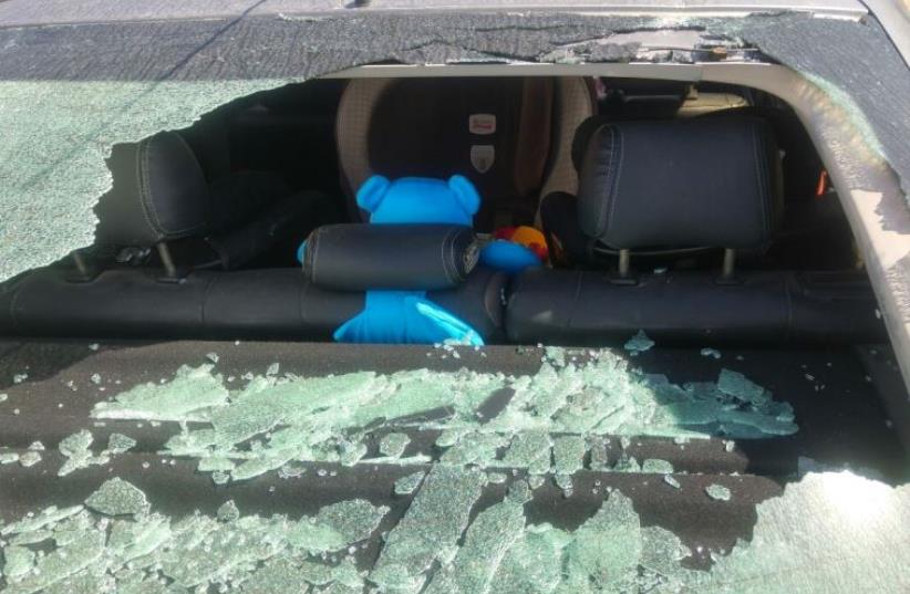 Rocks and stones severely damaged the car, just behind where the baby's car seat was situated  (photo credit: GUSH ETZION REGIONAL COUNCIL)