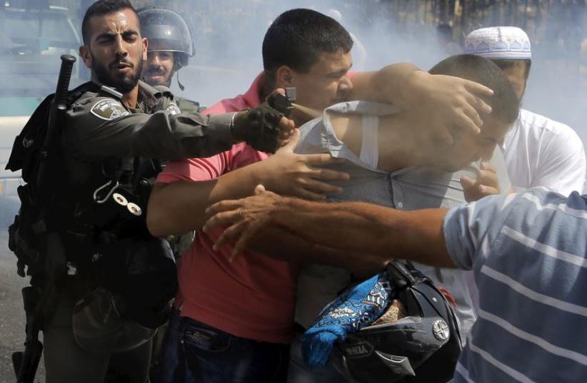 A Border Policeman uses pepper spray on a Palestinian man during clashes near the east Jerusalem neighborhood of Wadi al-Joz (photo credit: REUTERS)