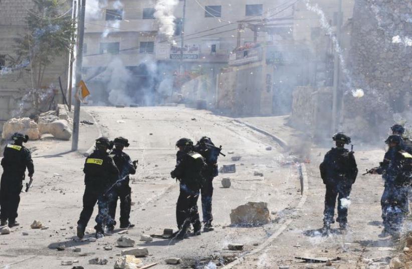 FIREWORKS FALL near policemen during clashes in the capital’s Isawiya neighborhood (photo credit: REUTERS)