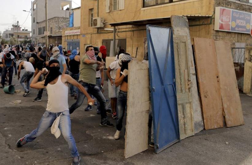 Palestinians throw stones towards Israeli police (not seen) during clashes in Shuafat, an Arab suburb of Jerusalem (photo credit: REUTERS)