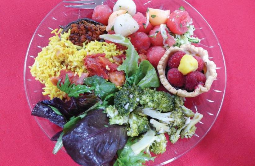 Tastes from a French kitchen: sausage with tomatoes and yellow rice, braised broccoli, melon salad, green salad, stuffed mushrooms and fruit tartlets (photo credit: YAKIR LEVY)