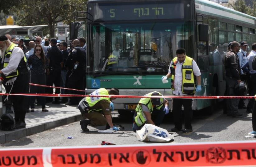 Israeli Zaka volunteers clean up blood stains at site where a 19-year-old Palestinian man stabbed a 25-year-old Jewish man in Jerusalem (photo credit: GALI TIBBON / AFP)