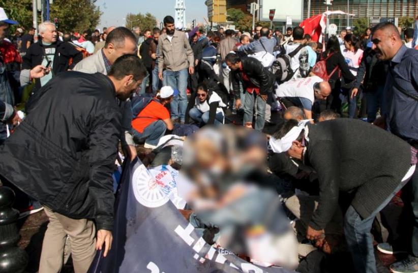 People lay on the ground as survivors surround them to offer help after an explosion during a peace march in Ankara, Turkey, October 10, 2015 (photo credit: REUTERS)