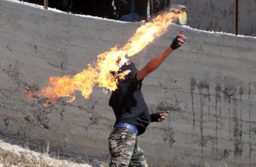 A Palestinian protester throws a Molotov cocktail towards Israeli security forces during clashes in the village of Beit Omar (photo credit: AFP PHOTO)