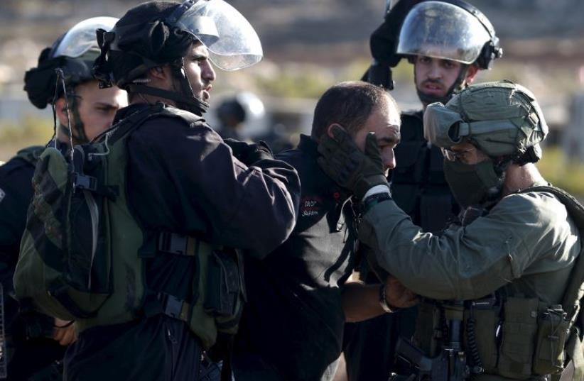 Israeli policemen detain a Palestinian protester during clashes near the Jewish settlement of Beit El (photo credit: REUTERS)