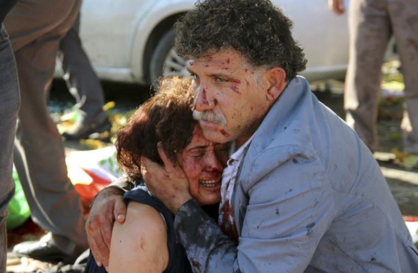 An injured man hugs an injured woman after an explosion during a peace march in Ankara, Turkey, October 10, 2015. (photo credit: REUTERS)