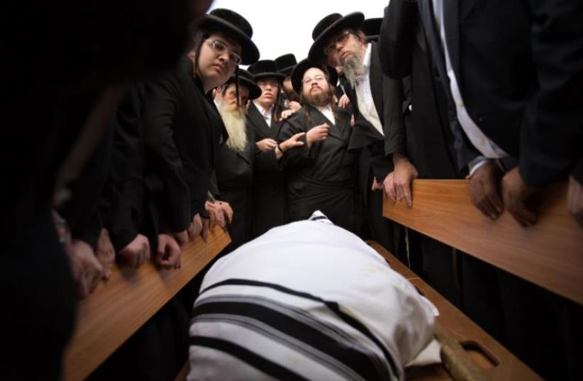 Ultra-Orthodox Jews mourn over the body of 60-year-old Rabbi Yeshayahu Krishevsky during his funeral in Jerusalem, October 13, 2015 (photo credit: AFP PHOTO)