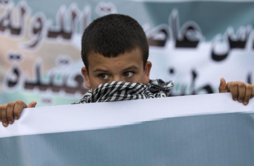An Arab Israeli boy holds a banner during a large demonstration in the northern town of Sakhnin (photo credit: AFP PHOTO)