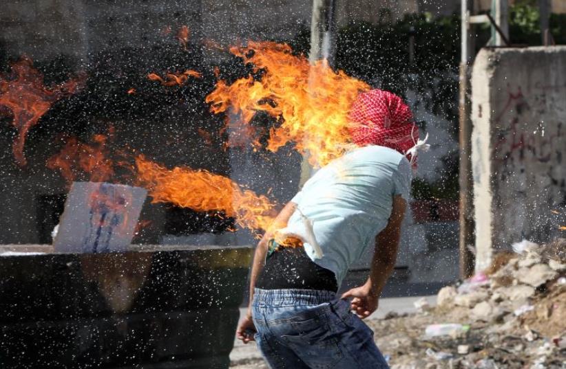 A Palestinian accidentally sets himself on fire after throwing a Molotov cocktail‏ (photo credit: HAZEM BADER / AFP)