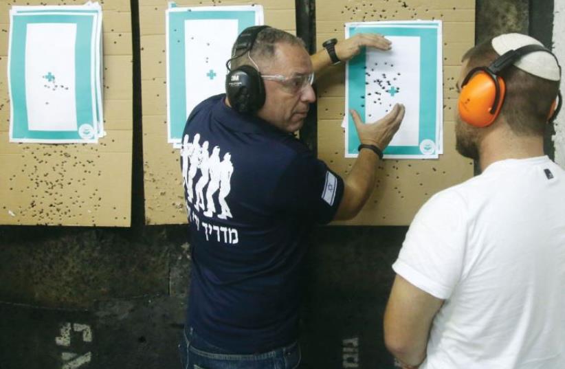Yair Yifrach an instructor at the Hagiva Arms shooting range, explains use of weapons and the target to a trainee (photo credit: MARC ISRAEL SELLEM/THE JERUSALEM POST)