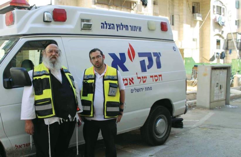 Zaka first responders Yossi Frankel (right) and Benzi Oring pose in front of one of the organization’s emergency vehicles (photo credit: SAM SOKOL)