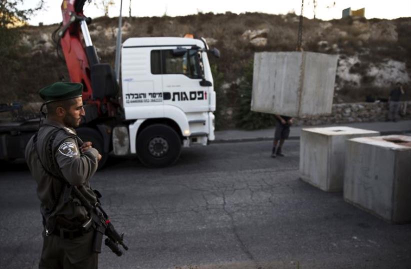 Border policeman stands next to a concrete barrier in Jabel Mukaber (photo credit: REUTERS)
