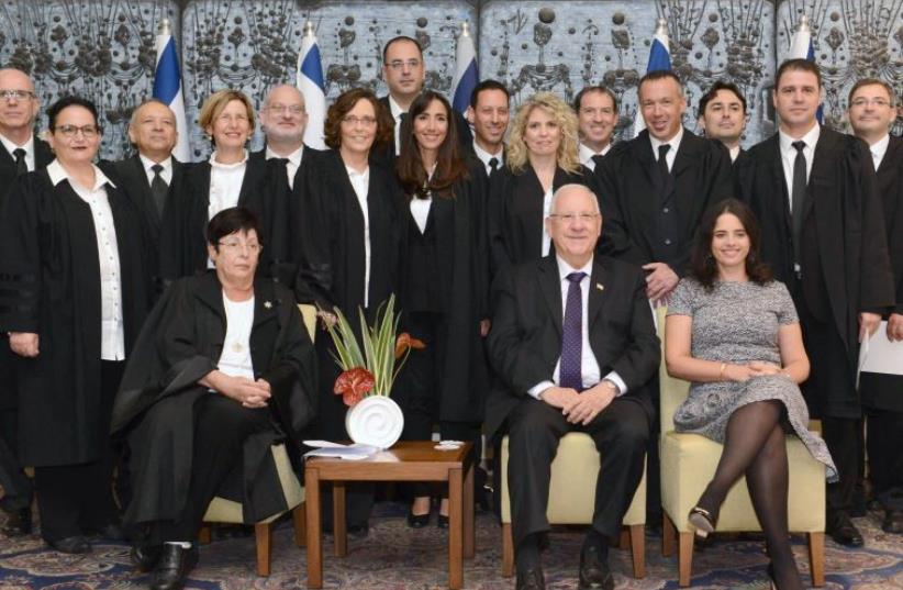 PRESIDENT REUVEN RIVLIN, flanked by Supreme Court President Miriam Naor (left) and Justice Minister Ayelet shaked, pose Thursday with 16 newly appointed judges at their swearing-in ceremony at the President’s Residence (photo credit: Mark Neiman/GPO)