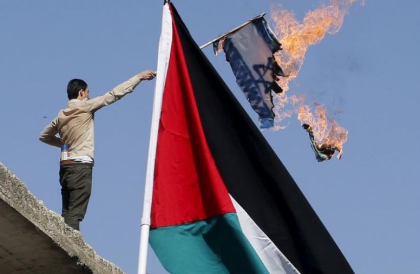 Protesters in Amman burn an Israeli flag during a protest to express solidarity with Palestinians (photo credit: REUTERS)