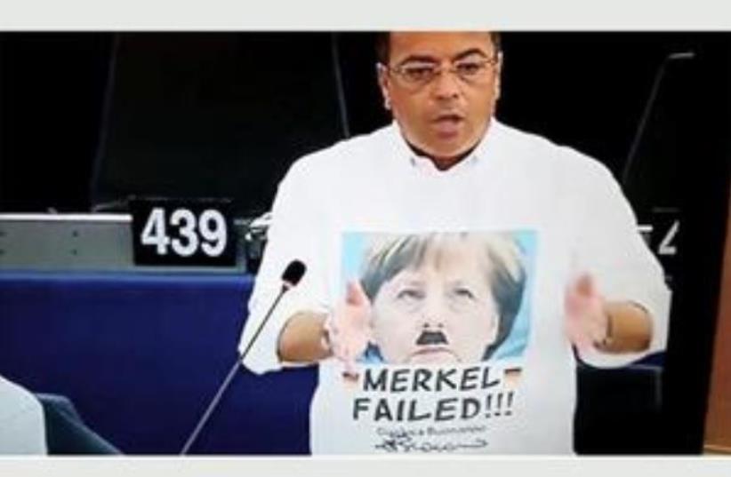 Italian MEP Gianluca Buonanno wears a T-shirt bearing an image of Chancellor Merkel combined with parts of an image of Adolf Hitler (photo credit: screenshot)