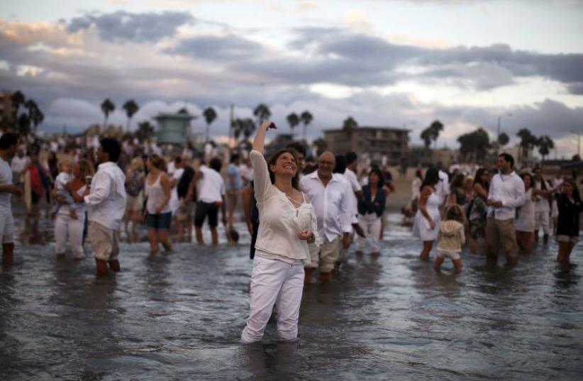 Rabbi Naomi Levy throws bread crumbs into the Pacific Ocean at the Nashuva Spiritual Community Jewish New Year celebration on Venice Beach in Los Angeles, California, United States September 14, 2015 (photo credit: REUTERS)