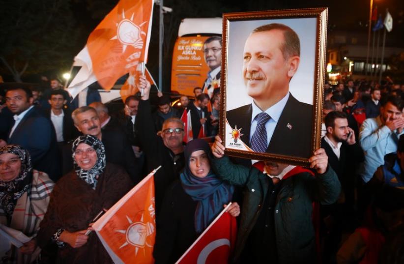Supporters wave flags and hold a portrait of Turkish President Tayyip Erdogan outside the AK Party headquarters in Istanbul, Turkey November 1, 2015 (photo credit: REUTERS)