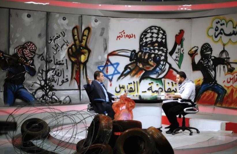 A PALESTINIAN presenter listens to Hamas official Salah al-Bardweel at a Gaza studio (photo credit: REUTERS)