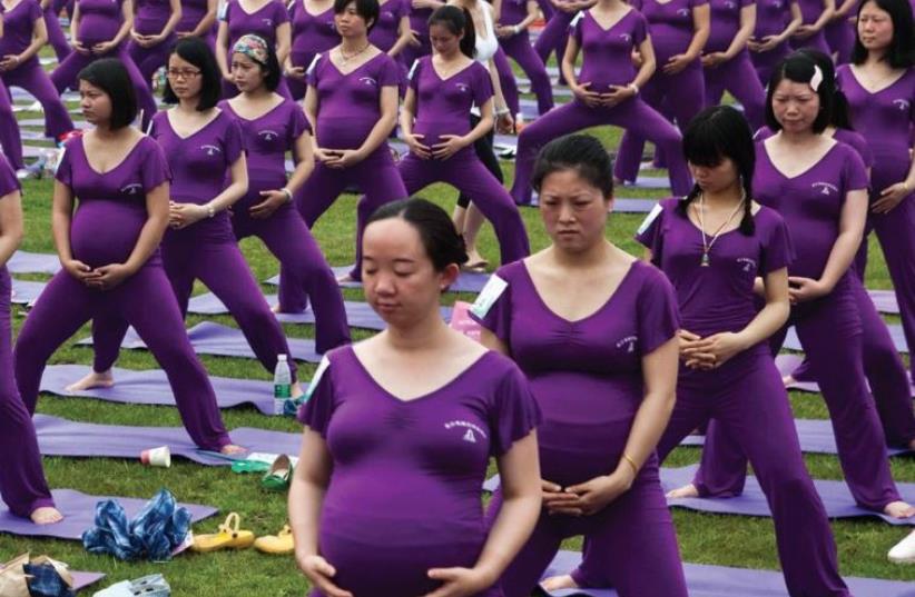 PREGNANT WOMEN practice yoga as they attempt to break the Guinness World Record for the largest prenatal yoga class, in Changsha, Hunan province last year (photo credit: REUTERS)