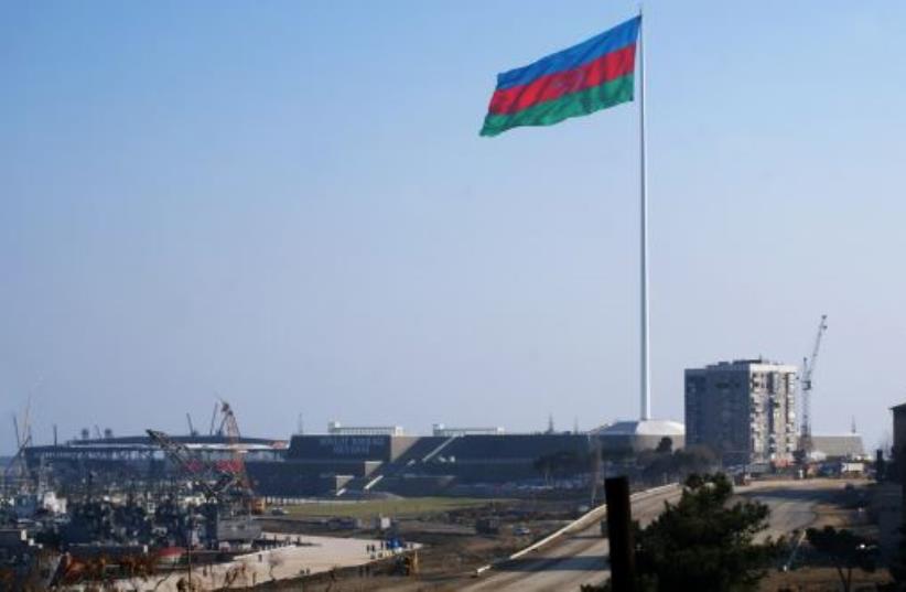 An enormous Azerbaijani flag flies above the construction site of a landmark concert hall on the Caspian Sea shoreline in Baku (photo credit: SAMIR ALIYEV/AFP)