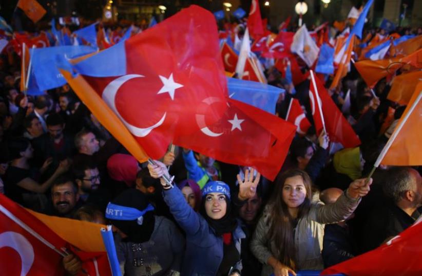 Women wave flags outside the AK Party headquarters in Ankara, Turkey (photo credit: REUTERS)