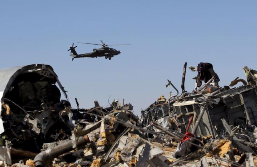 An Egyptian military helicopter flies over debris from a Russian airliner which crashed at the Hassana area in Arish city, north Egypt, November 1, 2015 (photo credit: REUTERS)