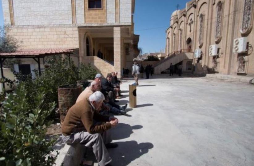 Displaced Assyrians, who fled from the villages around Tel Tamr, gather outside the Assyrian Church in al-Hasaka city, as they wait for news about the Assyrians abductees remaining in Islamic State hands, March 9, 2015.  (photo credit: RODI SAID / REUTERS)