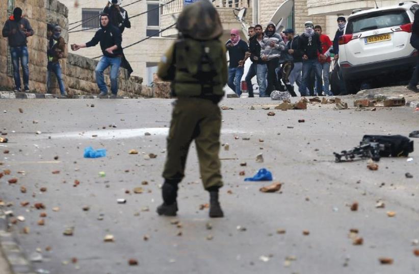 Palestinians hurl rocks at IDF soldiers during clashes in Ramallah (photo credit: REUTERS)
