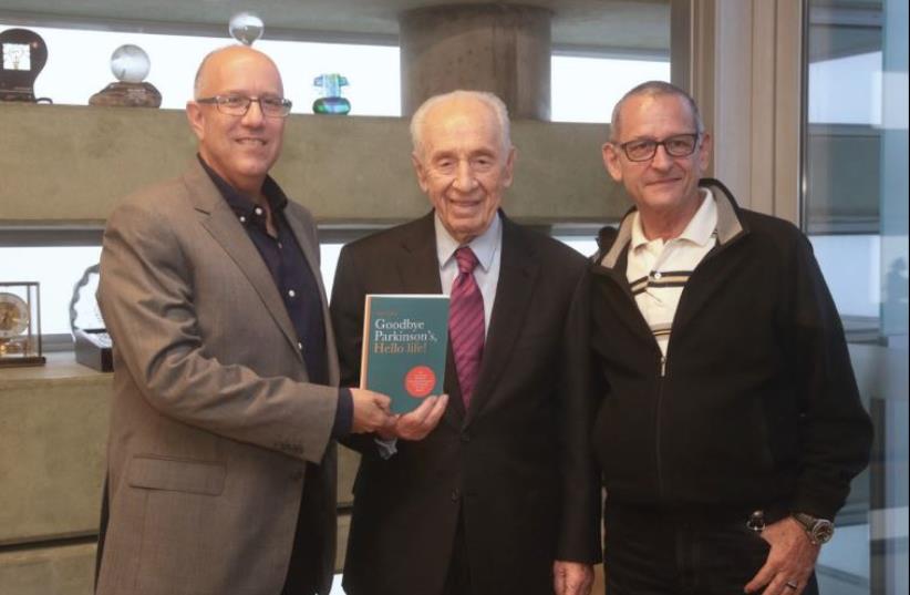 ‘JERUSALEM POST’ Managing Editor David Brinn (left) and Parkinson’s disease therapist Alex Kerten present former president Shimon Peres with a copy of their forthcoming book. (photo credit: MARC ISRAEL SELLEM)
