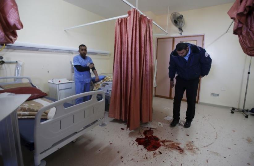 A medic looks at blood stain of a Palestinian man who was killed by Israeli undercover forces during a raid at Al-Ahly hospital in the West Bank city of Hebron November 12, 2015. (photo credit: REUTERS)