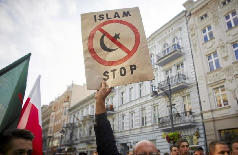 A protester from a far-right organization holds up a sign which reads "Islam Stop" during a protest against refugees in Lodz, Poland (photo credit: REUTERS)