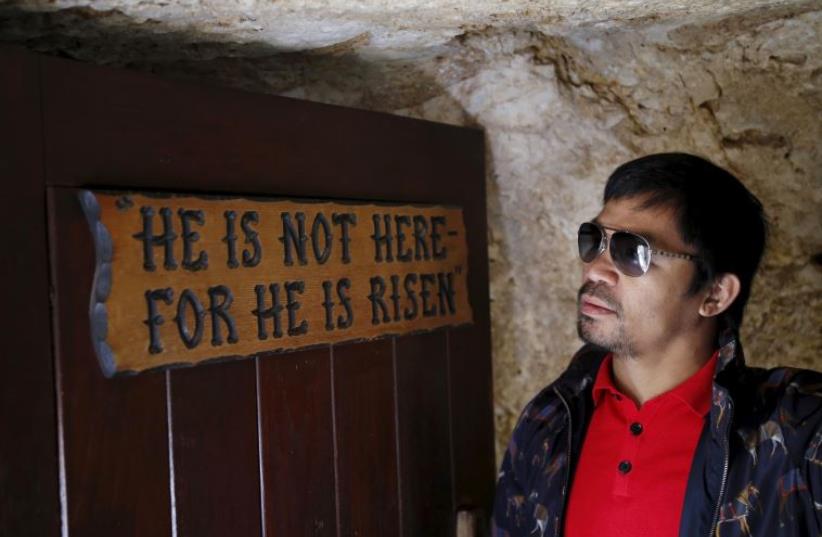 Filipino boxer Manny Pacquiao stands next to a sign during a visit to The Garden Tomb site outside Jerusalem's old city November 21, 2015 (photo credit: REUTERS)