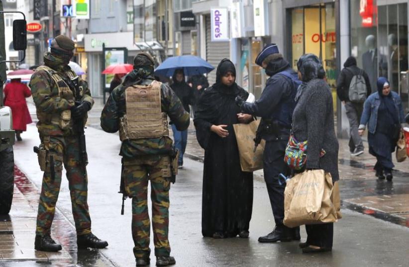 Belgian soldiers and a police officer control the documents of a woman in a shopping street in central Brussels, November 21, 2015 (photo credit: REUTERS)