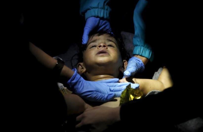 Volunteer doctors and paramedics try to revive a baby after a boat carrying more than 200 refugees and migrants sunk while crossing part of the Aegean sea from Turkey, on the Greek island of Lesbos (photo credit: REUTERS)