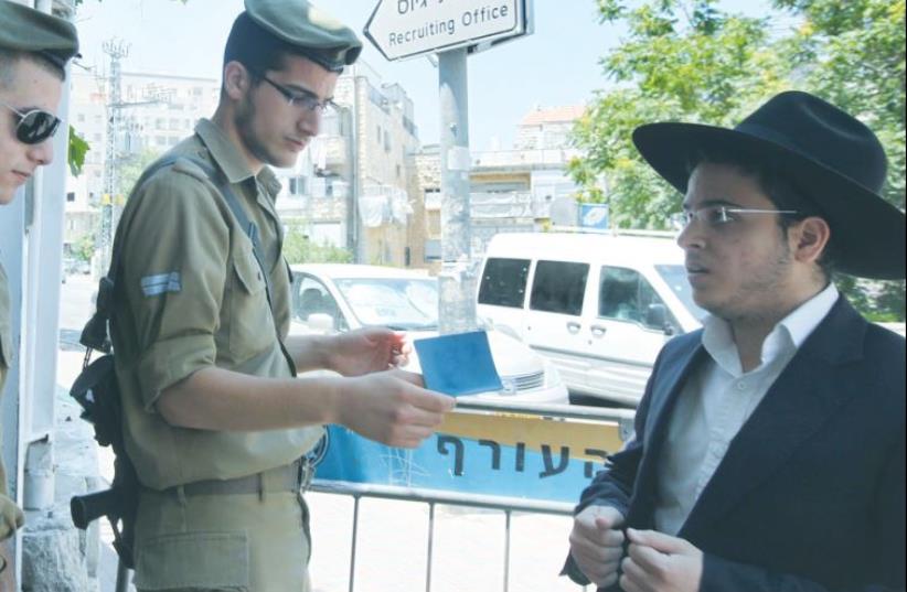 A HAREDI MAN shows his call-up notice to soldiers to allow him entry to the Jerusalem recruitment office (photo credit: MARC ISRAEL SELLEM)