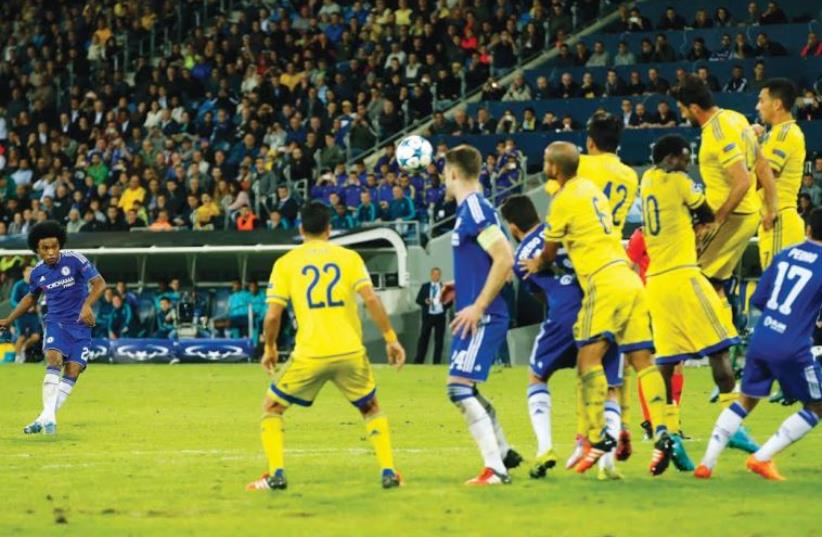 CHELSEA MIDFIELDER Willian (left) sends the ball soaring over the line on a free kick for the Blues’ second goal in their 4-0 Champions League victory over Maccabi Tel Aviv last night at Sammy Ofer Stadium in Haifa.  (photo credit: REUTERS)