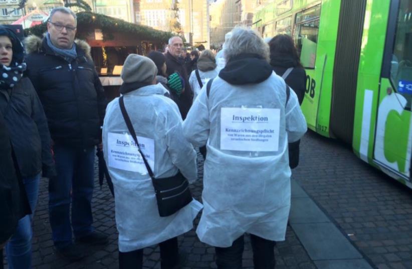 Activists wearing signs posted on their backs, which read “Inspection obligation from products from the illegal Israeli settlements." (photo credit: JAN-PHILIPP HEIN)