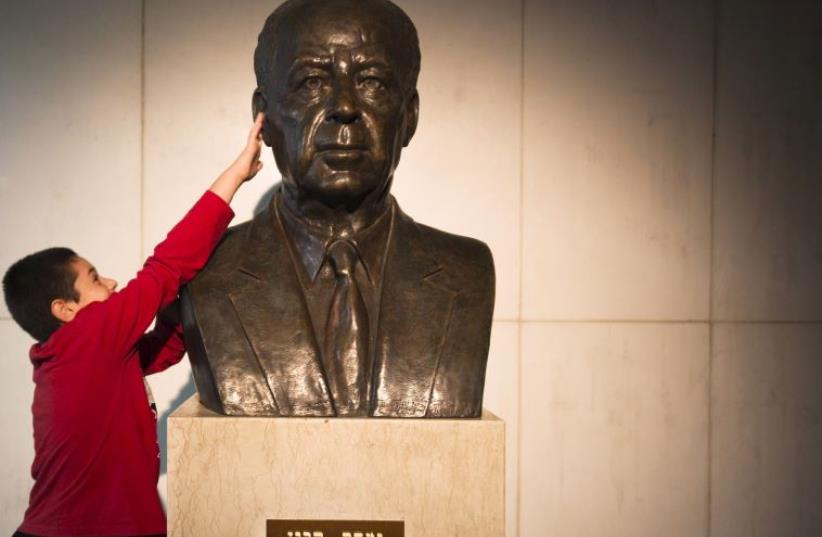 A boy touches the bust of Yitzhak Rabin before a rally commemorating the 20th anniversary of his assassination in Tel Aviv, October 31 (photo credit: REUTERS)