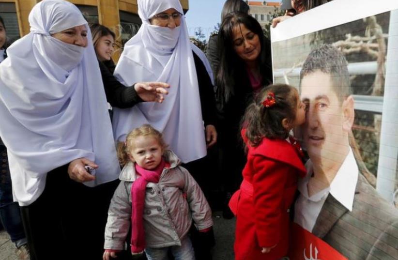 The daughter of Druze policeman Wael Hamzeh Homs, who was captured in Arsal by the al Qaeda-linked Nusra Front, kisses his picture as relatives react in celebration for his release, outside a tent that was erected last year during an open-ended sit-in near the government palace in downtown Beirut, D (photo credit: REUTERS)
