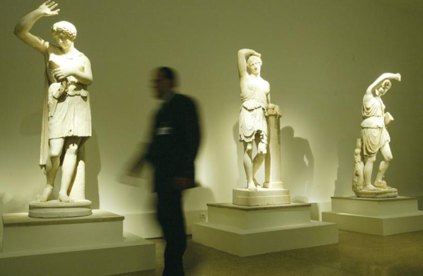 A guard walks past statues of wounded Amazones, made between 400 and 350 BCE, at the National Archeological Museum in Athens (photo credit: REUTERS)