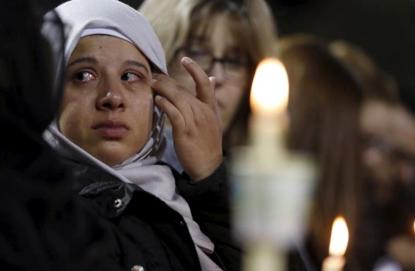 An attendee reflects on the tragedy of Wednesday's attack during a candlelight vigil in San Bernardino, California (photo credit: REUTERS)